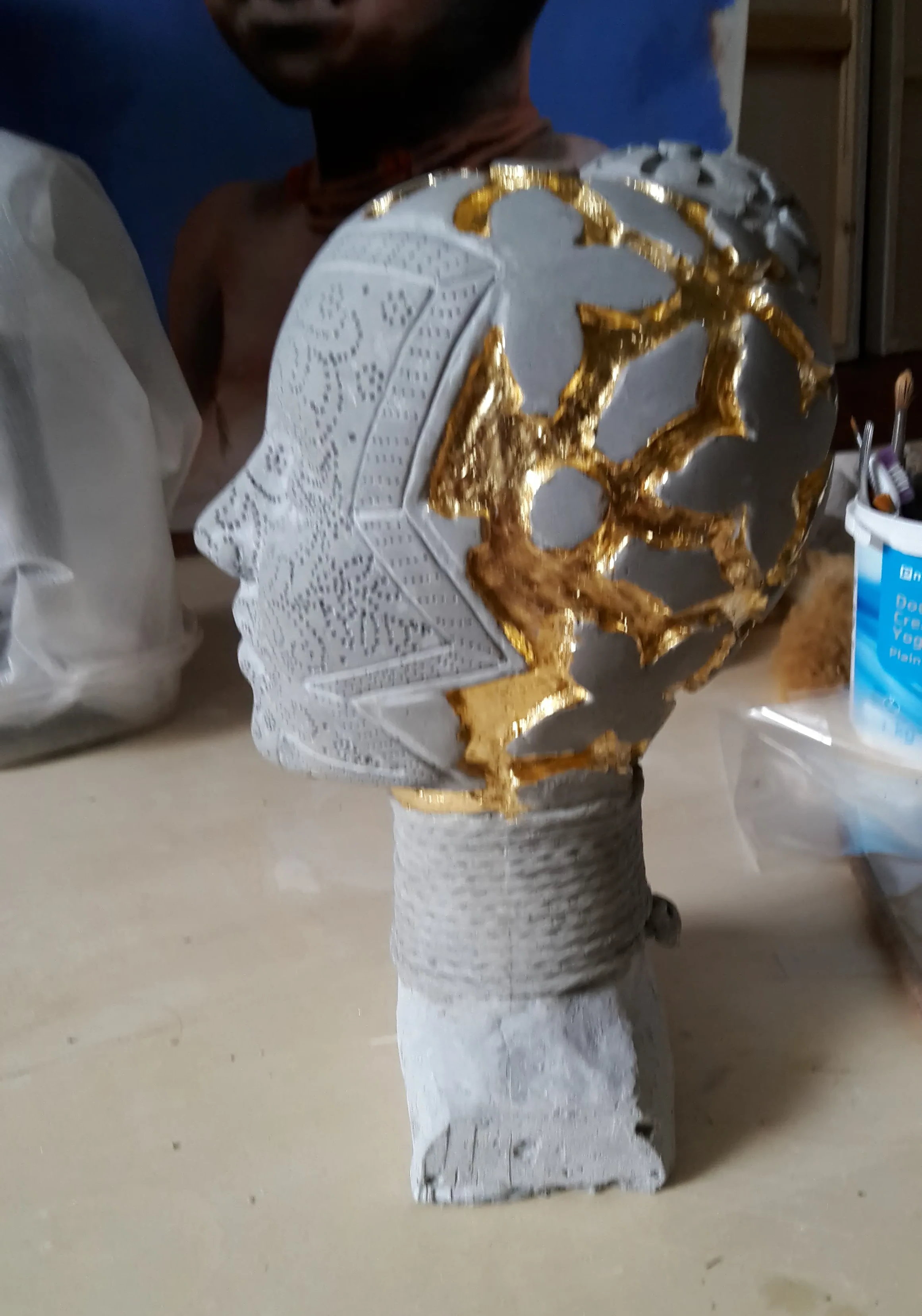 Process photo of applying gold leaf to the sculpture in the studio.